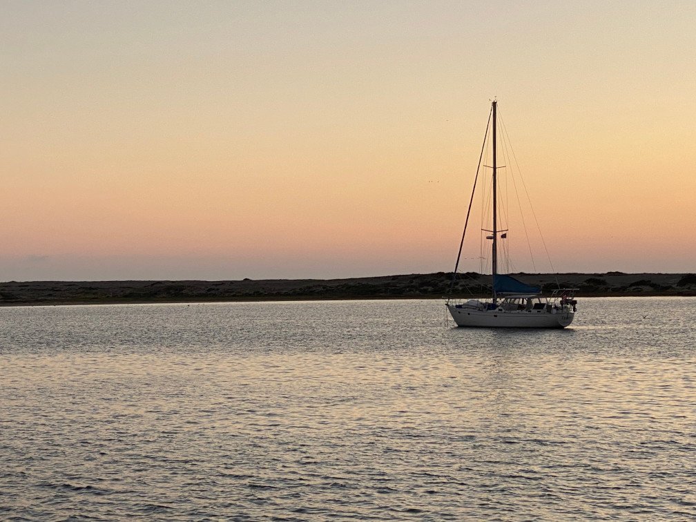 A sail boat anchored in Morro Bay during the evening.