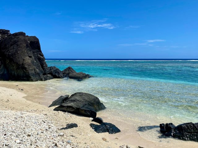 View of the large black rocks on Black Rock Beach in Rarotonga, Cook Islands