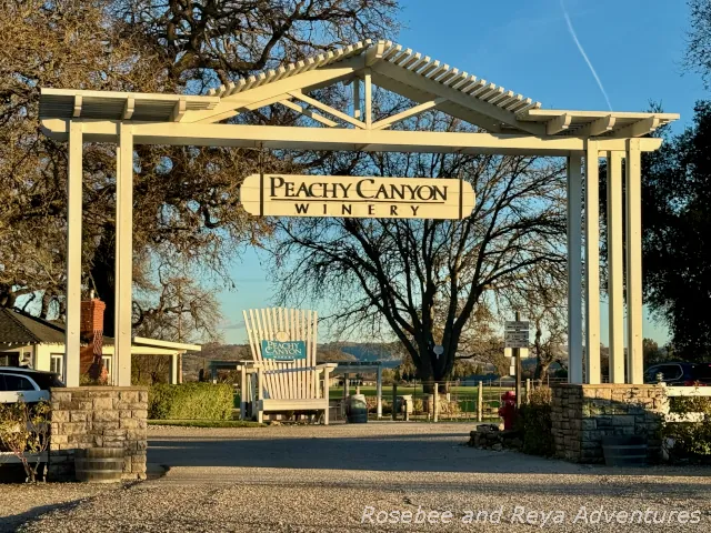 Picture of the outside entrance to the Peachy Canyon Winery parking lot with the large white chair that is in front of the tasting room in the background